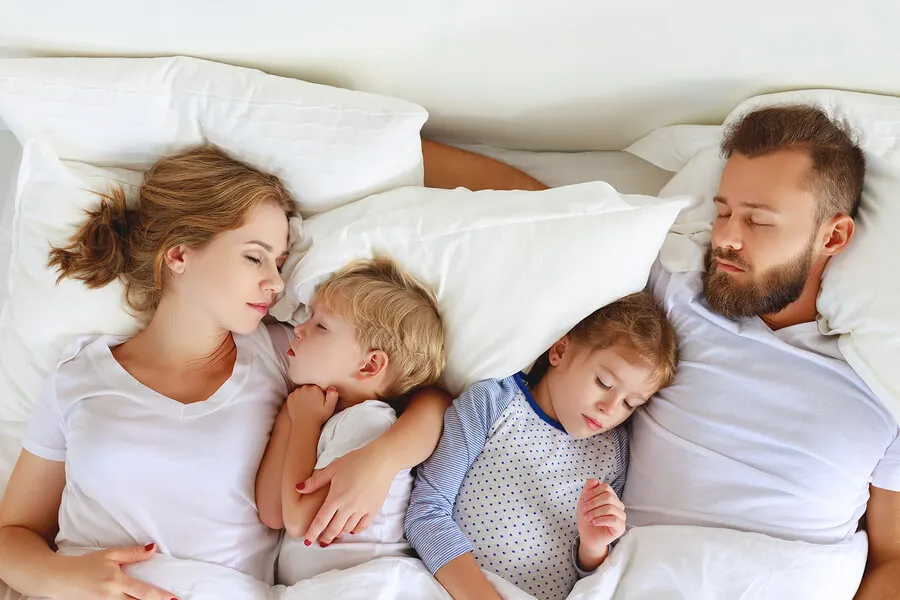 Familia practicando el colecho en la cama.