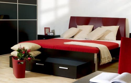 Cama con detalles rojos en una habitación moderna.