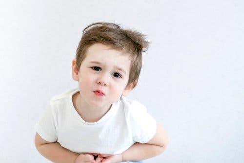 Niño con las manos sobre el estómago y un gesto de dolor.