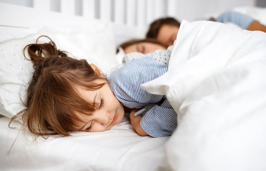 Niña durmiendo en la cama con sus padres (colecho).