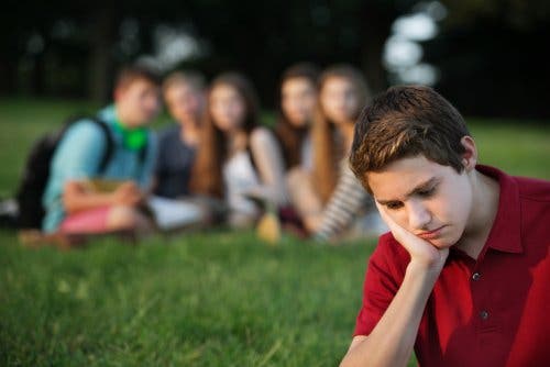 Grupo de adolescentes riéndose de un chico.