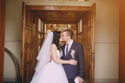 Novios dándose un beso a la puerta de la iglesia