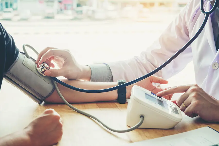 Médico midiendo la presión arterial a un paciente.