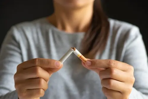 mujer rompiendo cigarrillo