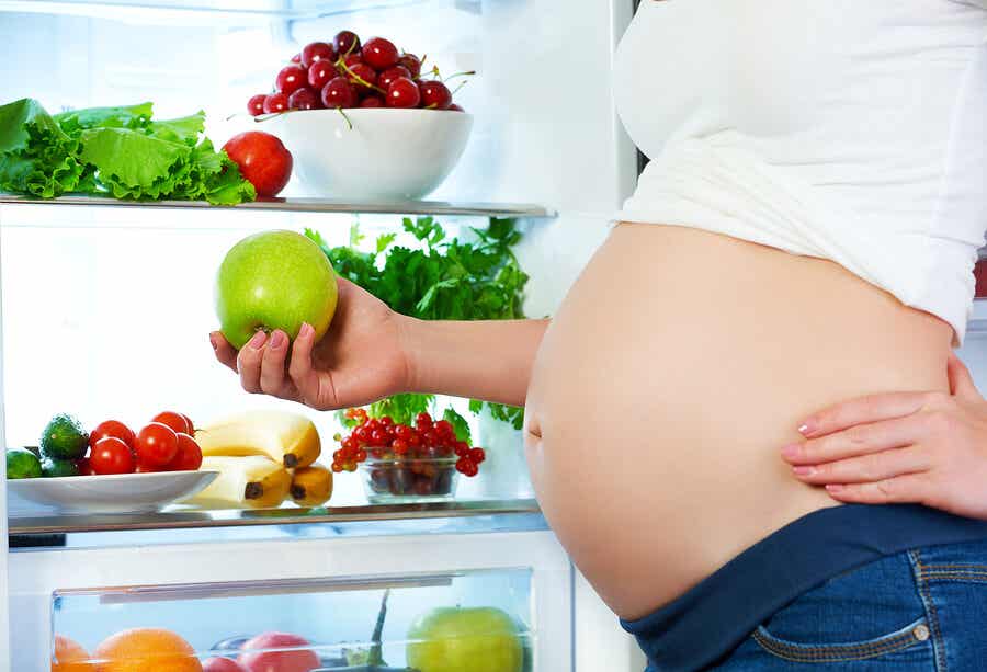 Embarazada en nevera con fruta