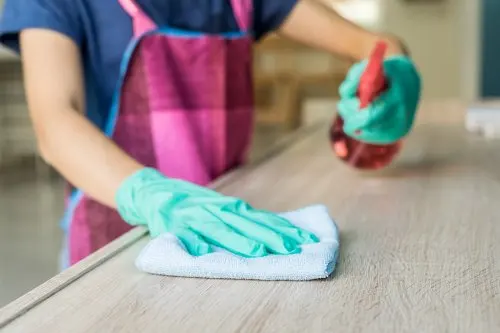 Limpiando un mueble de madera con un spray y un trapo