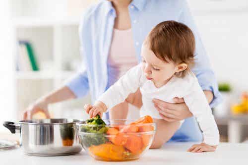 Mamá con bebé cocinando vegetales
