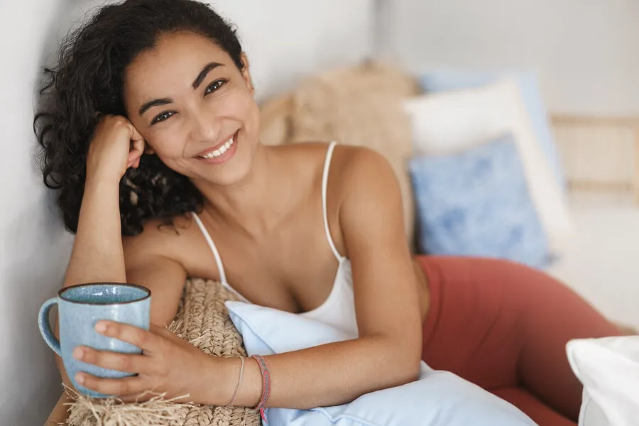 Mujer en el sofá sosteniendo una taza con una bebida natural