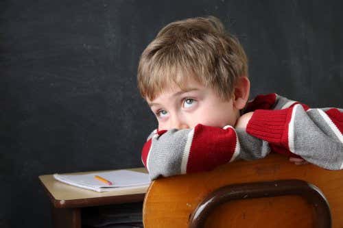 Niño sentado en un pupitre sin prestar atención: TDAH