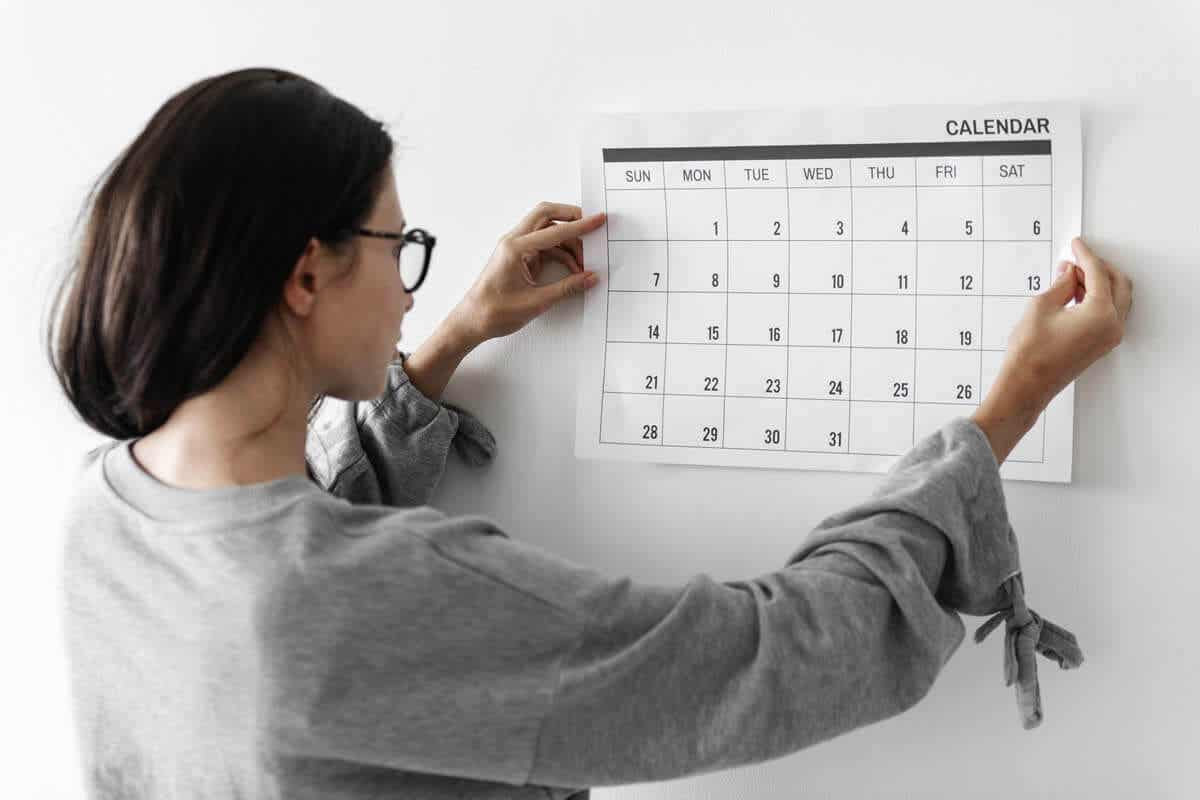 Mujer colgando un calendario en la pared.