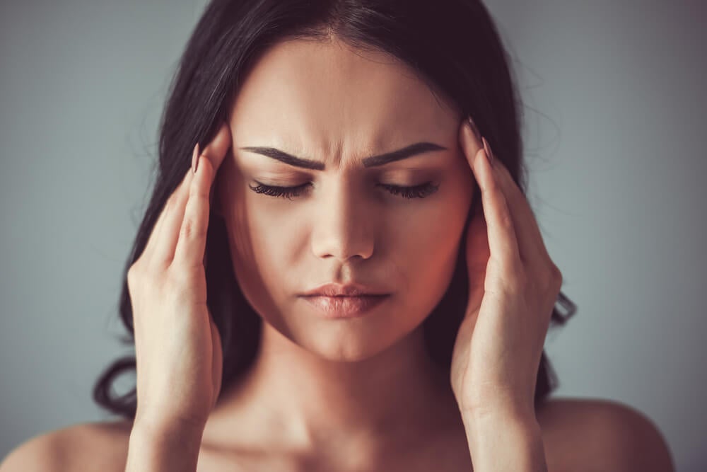 mujer apretándose las sienes debido a un fuerte dolor de cabeza