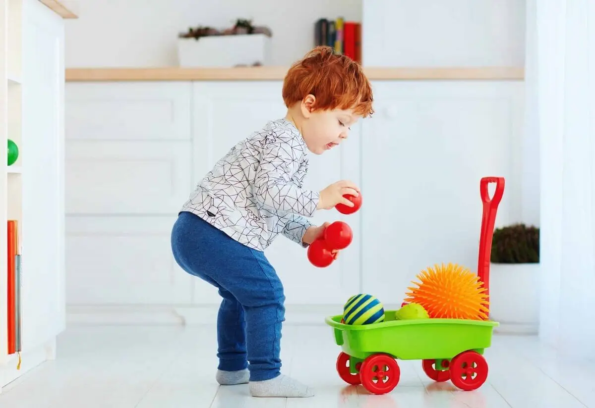 Niño ordenando sus juguetes.