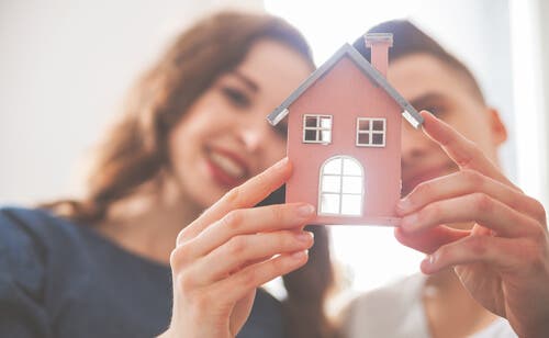 Pareja sosteniendo una casa de juguete