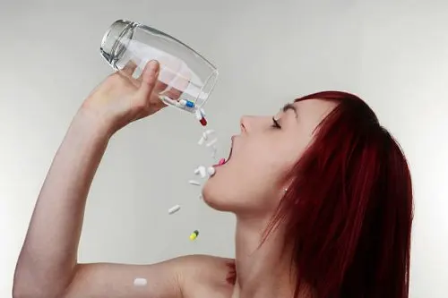 Mujer con un vaso lleno de pastillas