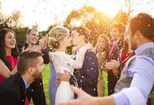 Novios besándose en la boda junto a padrinos y familiares