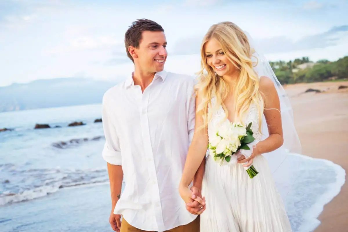 Novio cogiendo de la mano a la novia en una playa