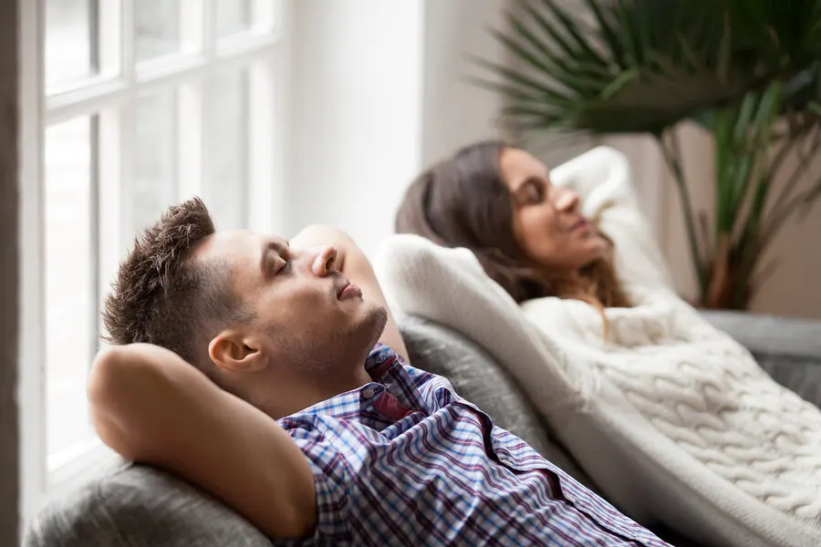 Pareja joven en el sofá sintiendo bienestar.