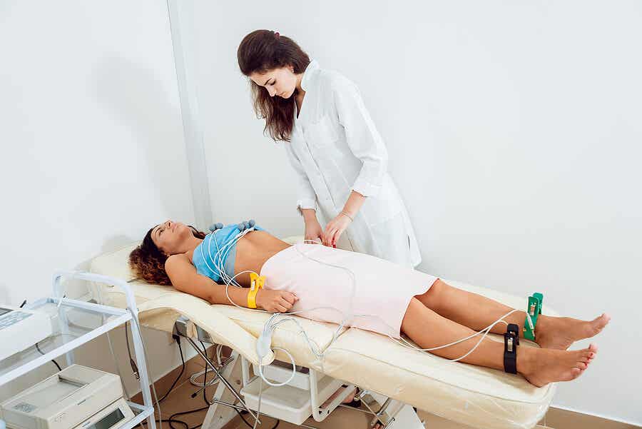 Doctora haciéndole un electrocardiograma a una paciente mujer.