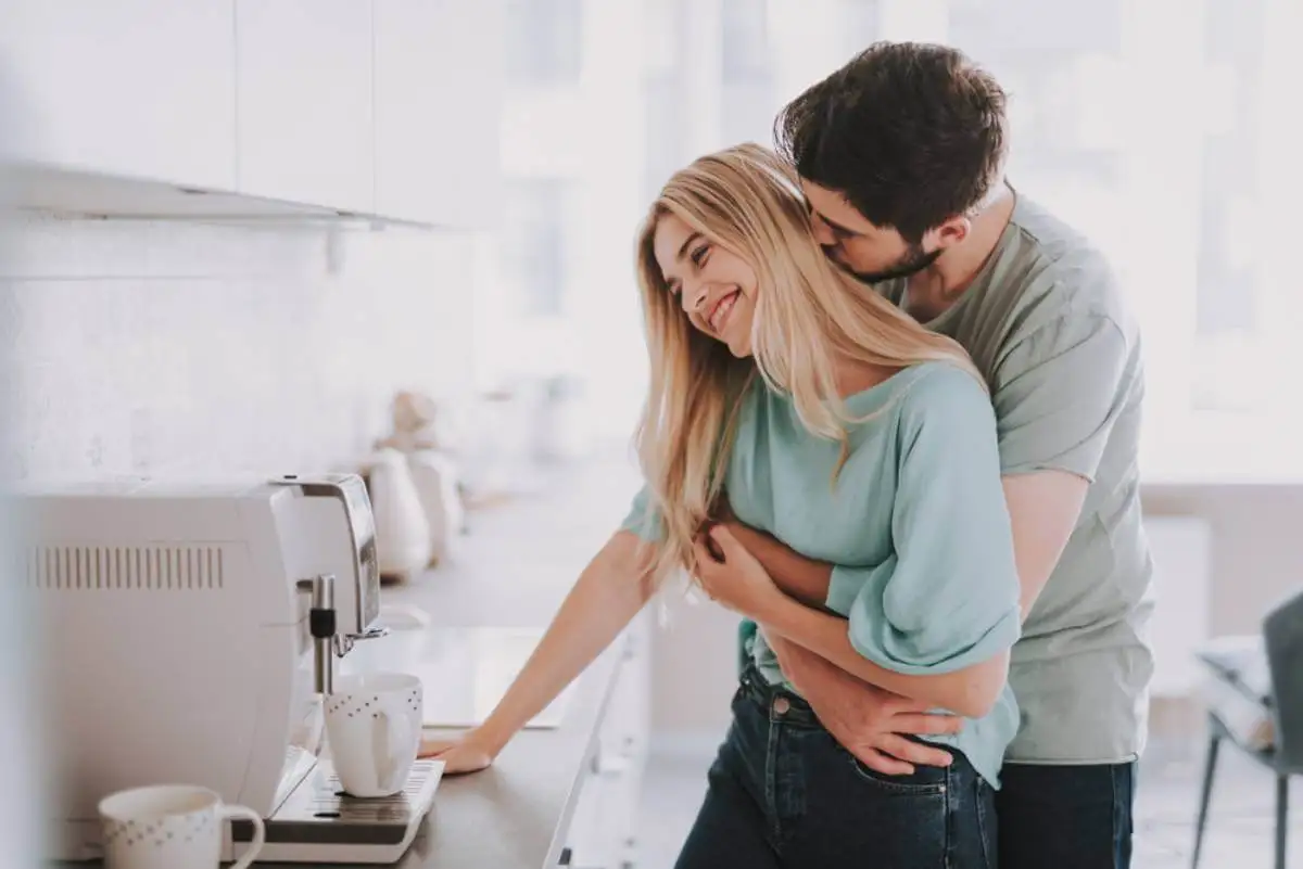 Pareja besándose en la cocina: Temas que debéis discutir regularmente como pareja