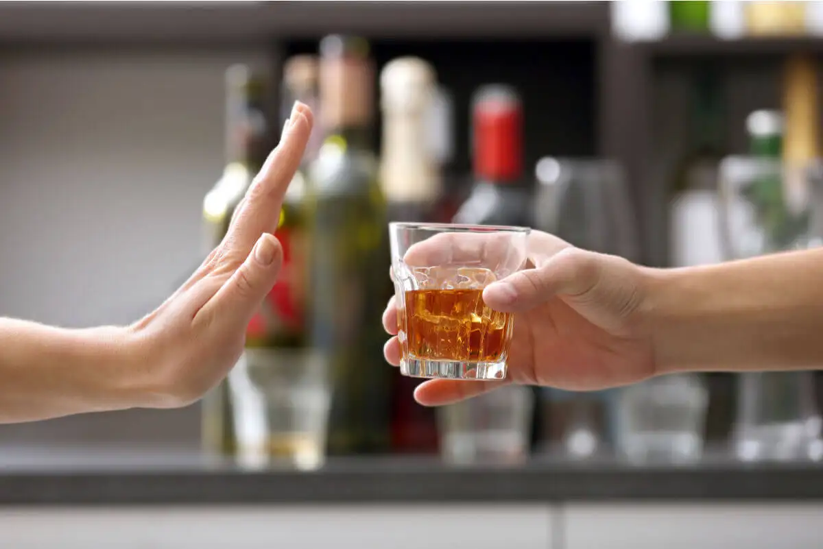 Mano rechaza vaso con alcohol.