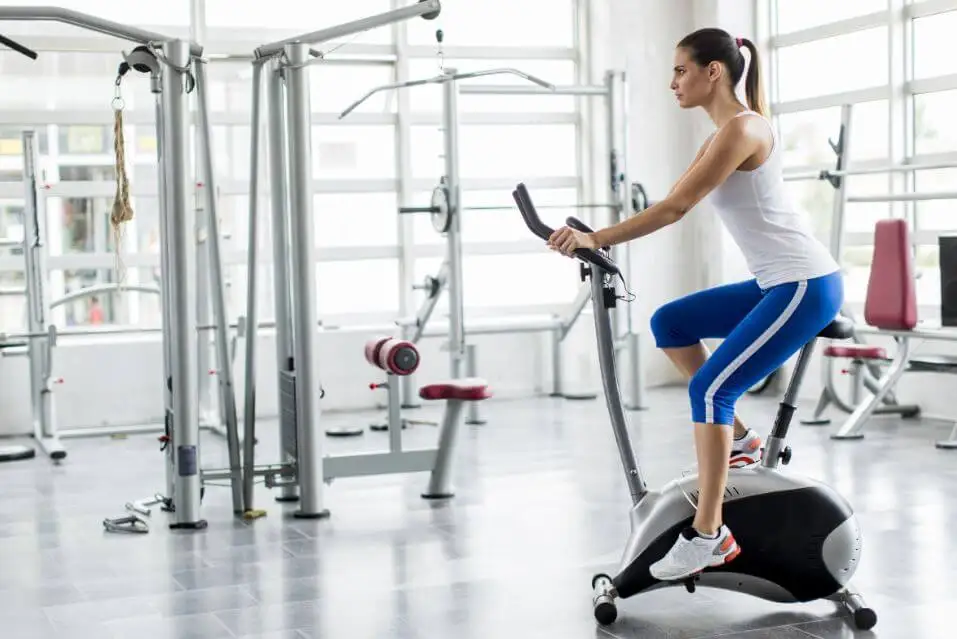 Mujer haciendo bicicleta estática en el gimnasio.