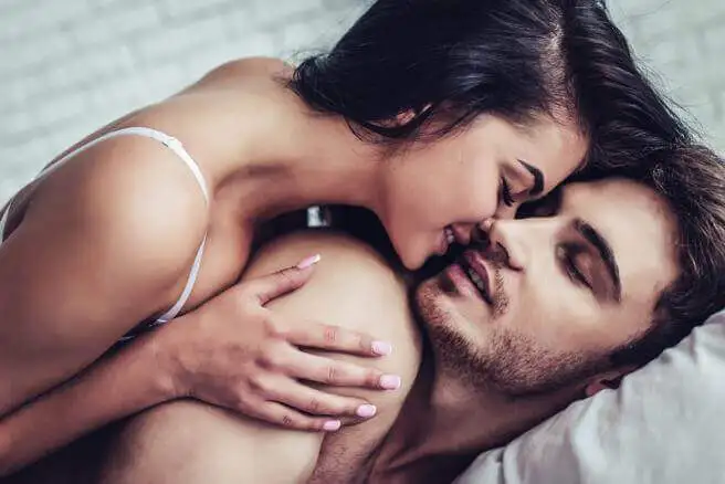 Pareja dándose un beso en la cama