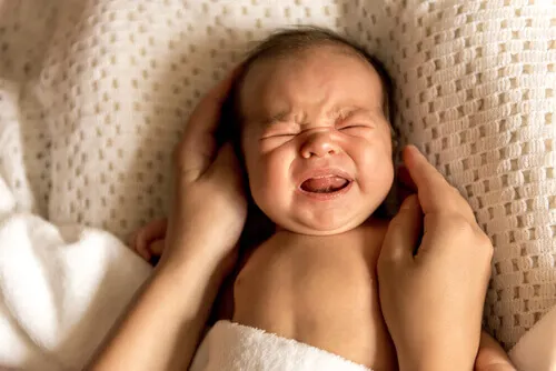 Bebé llorando en la cama.