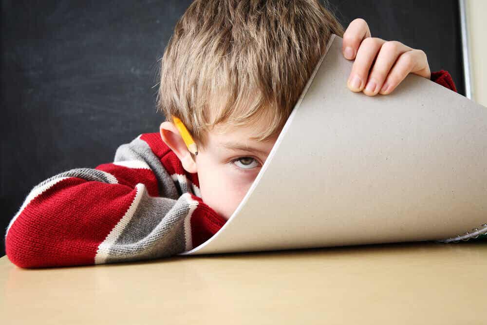 Lernen mit ADHS - kleiner Junge versteckt sich hinter einem Block