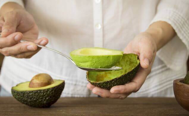Persona sacándole la pulpa al aguacate.