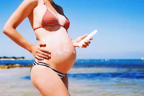 Embarazada echándose crema solar.