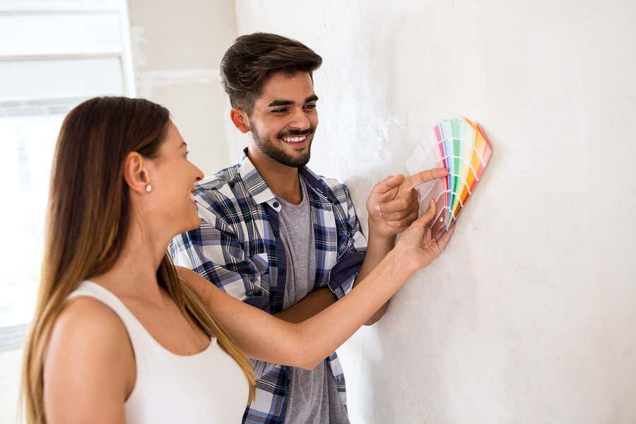 Couple choisissant des couleurs pour peindre des rayures sur un mur.
