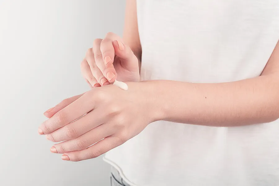 Persona aplicándose crema Diprogenta en la mano.