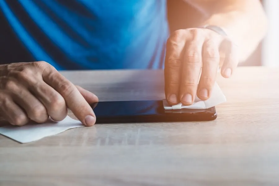 Homme qui désinfecte son téléphone après avoir eu la grippe.