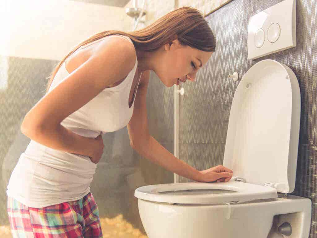 Femme qui vomit dans les toilettes.
