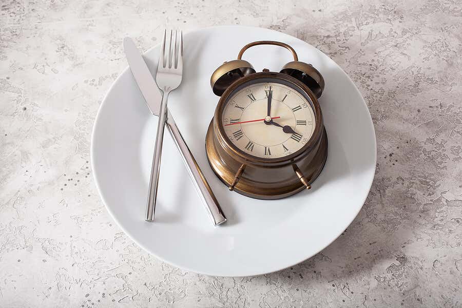 Übermäßiges Essen nach dem Sport - Teller mit Besteck und einer Uhr