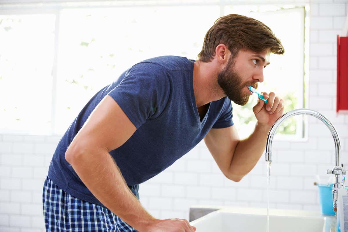 Hombre cepilla sus dientes.