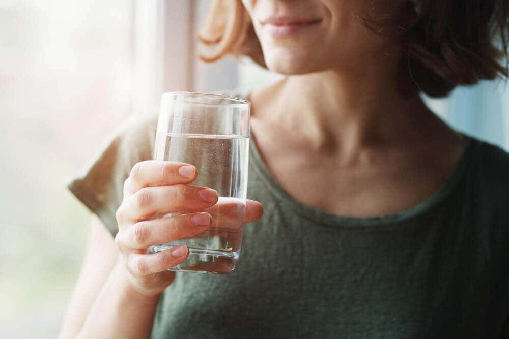 Mujer se hidrata para mejorar la mucosa cervical.