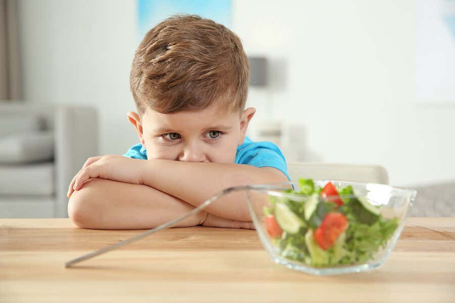 Vegetarische Ernährung für Kinder - kleiner Junge, der keinen Salat essen möchte