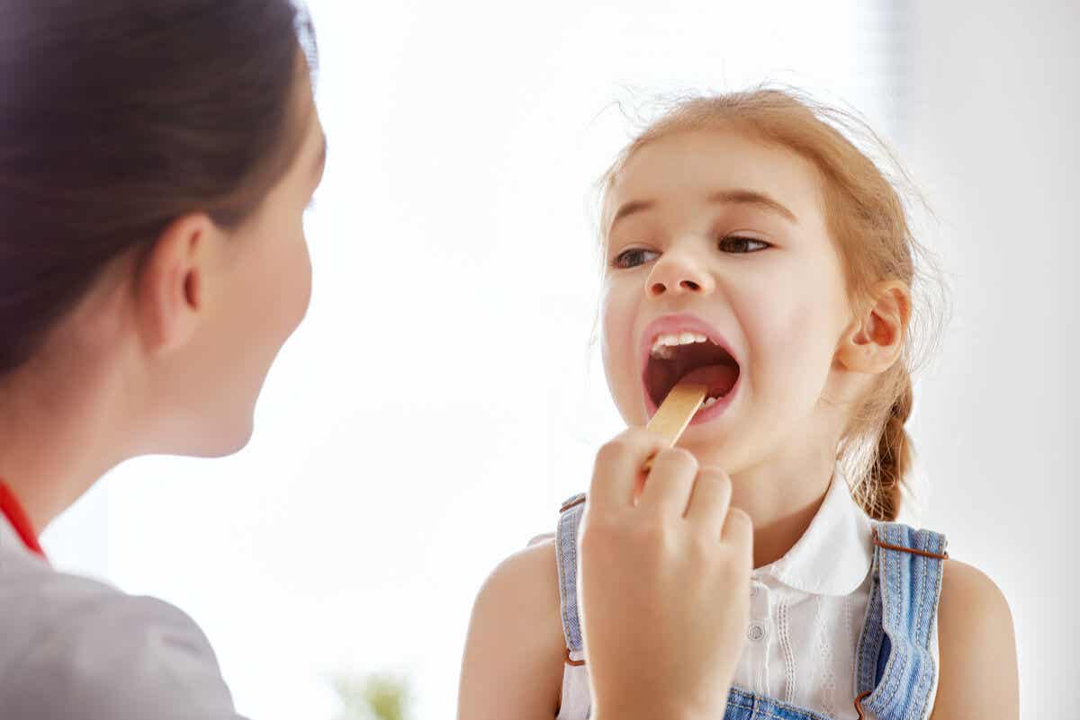 Pediatra ispeziona la gola a una piccola paziente.
