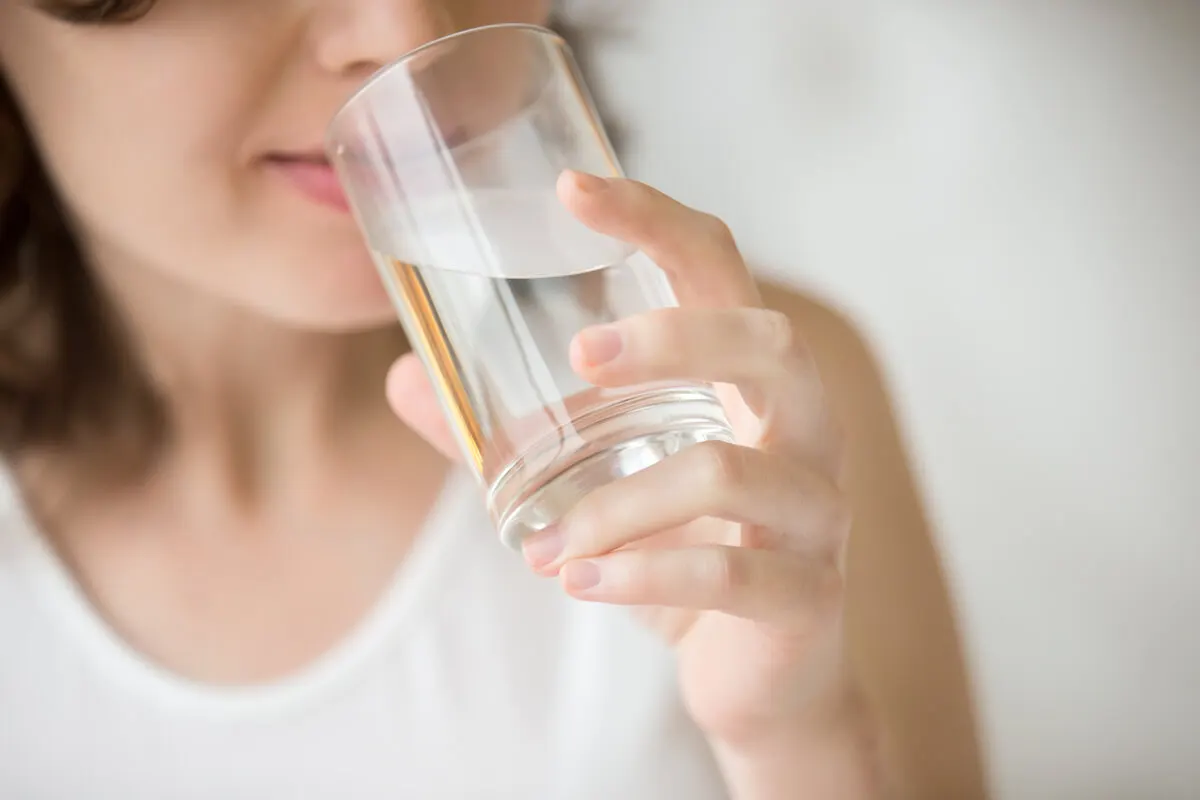 Mujer toma agua de vaso