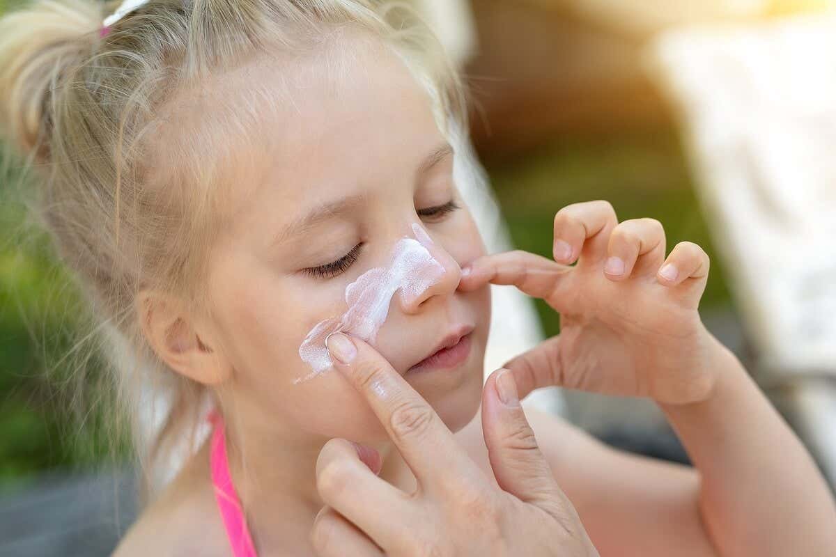 Hautpflege im Sommer - Mädchen mit Sonnencreme im Gesicht
