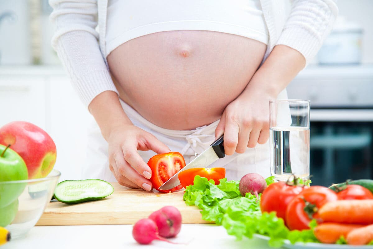 Mulher grávida cortando salada