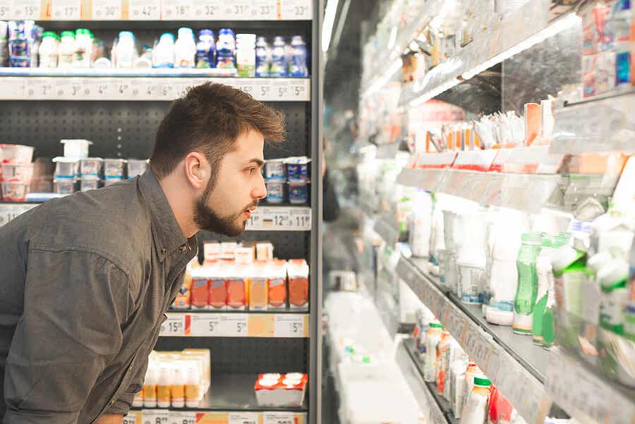 Hombre mirando productos lácteos en el supermercado.