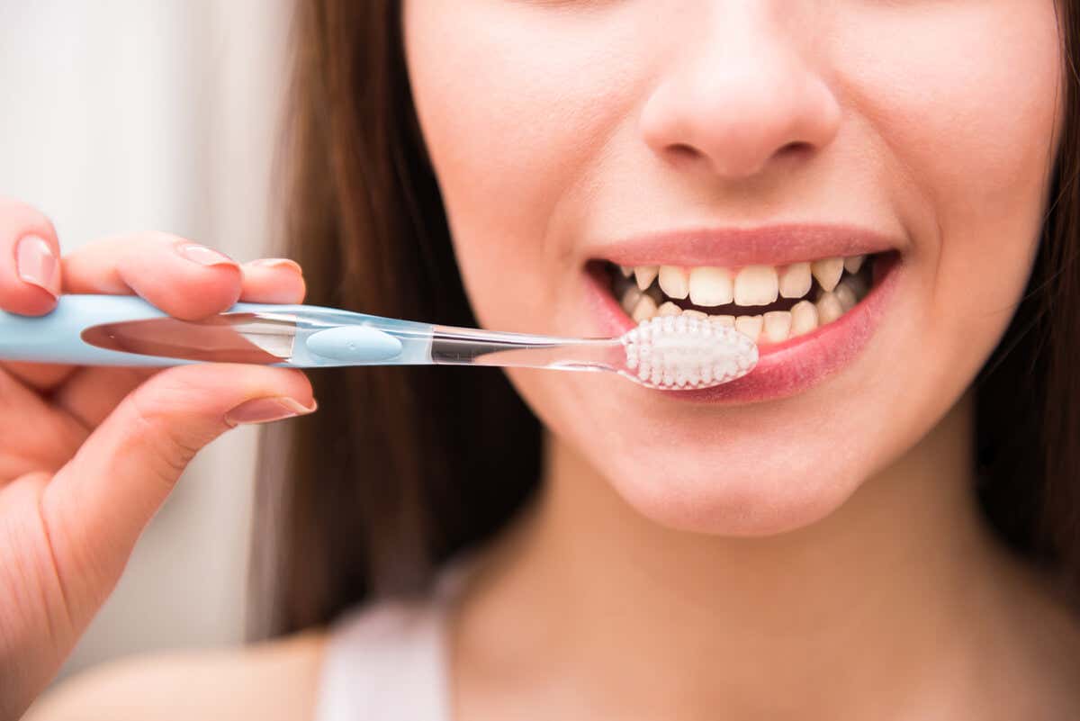 Mujer cepilla sus dientes por padecer xerostomía.