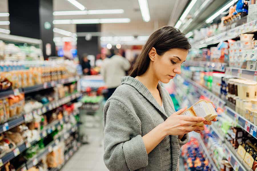 Mujer con yogures en el supermercado revisando la seguridad alimentaria