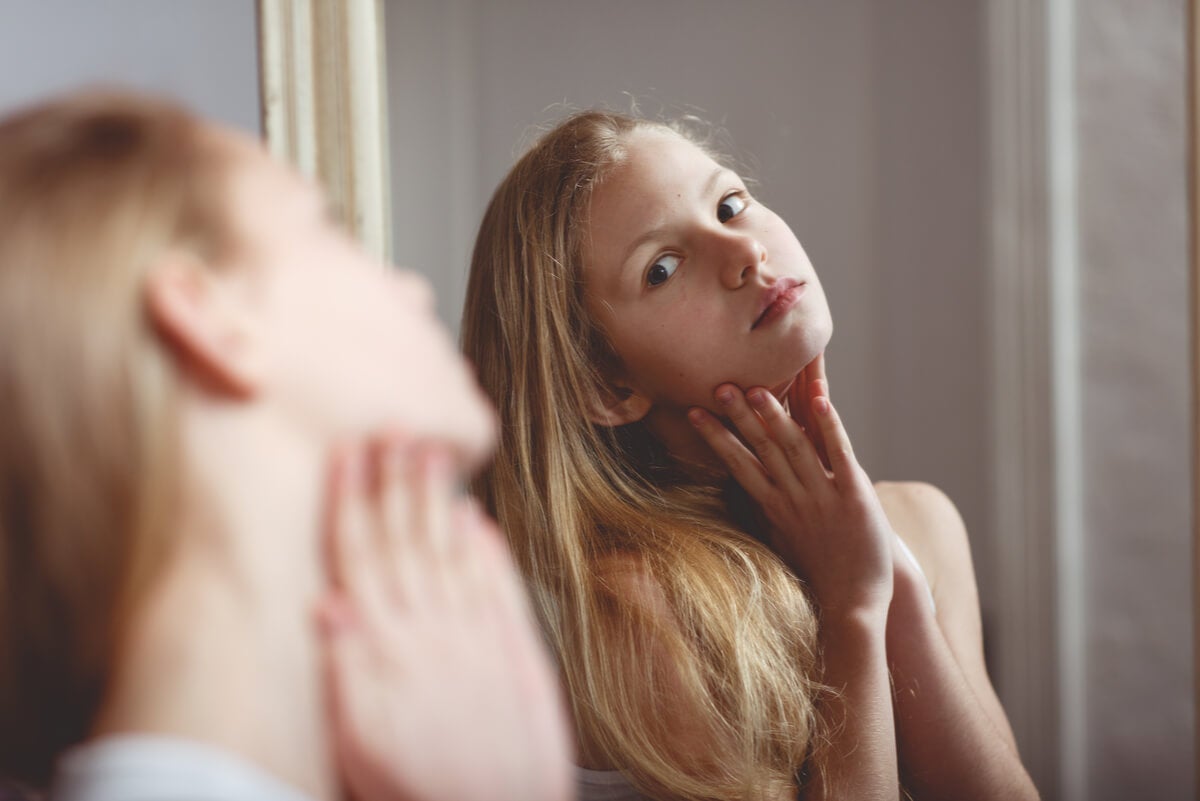 Une adolescente se regarde dans le miroir.