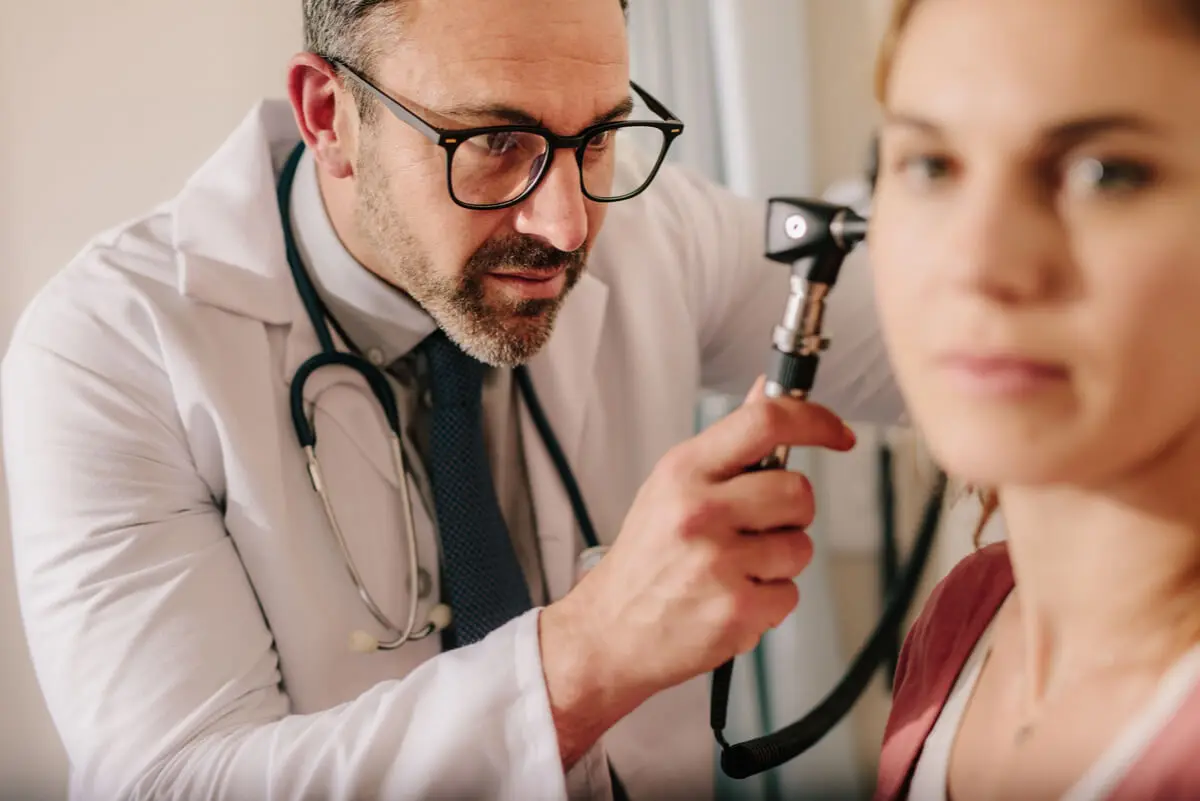 Médico revisa oreja de coliflor.