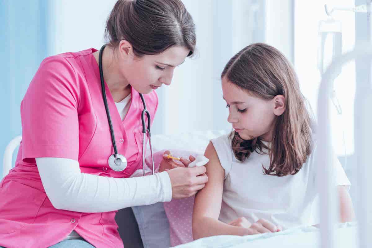 Niña recibiendo vacuna por una enfermera porque es importante vacunar a los niños.