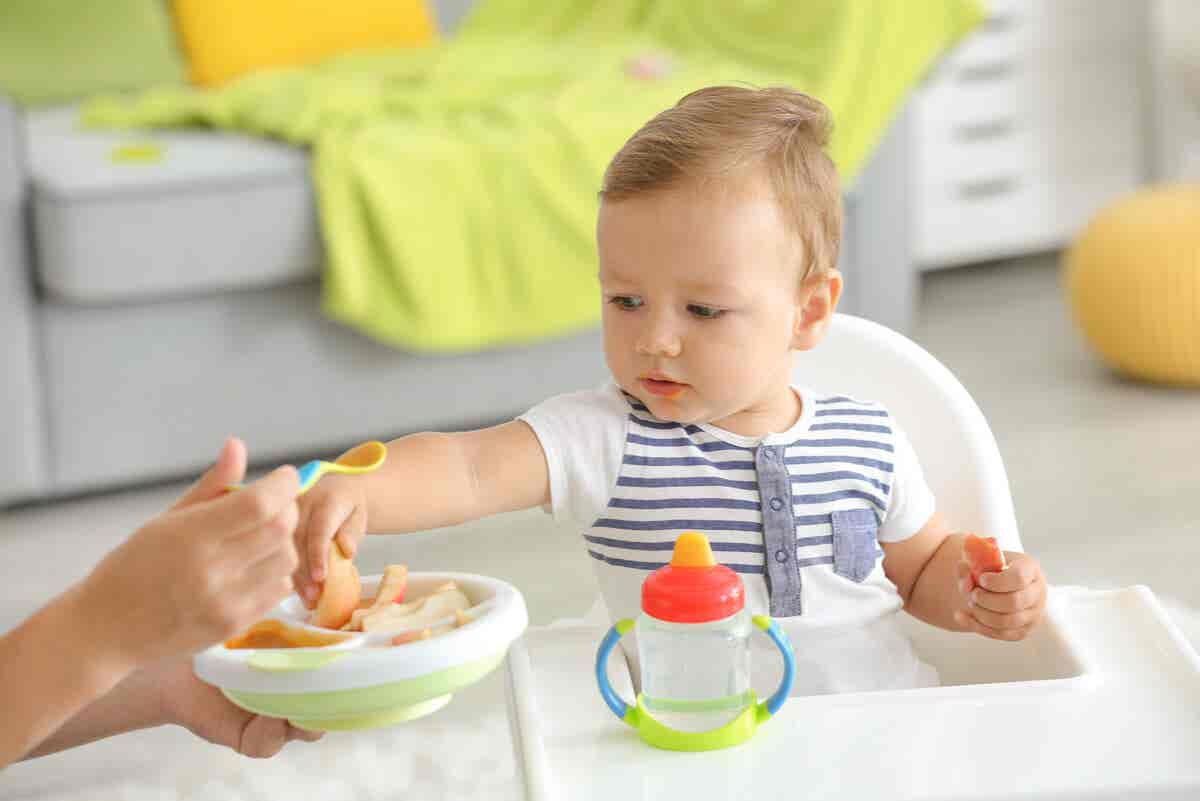 Bebé toma alimentos con la mano.