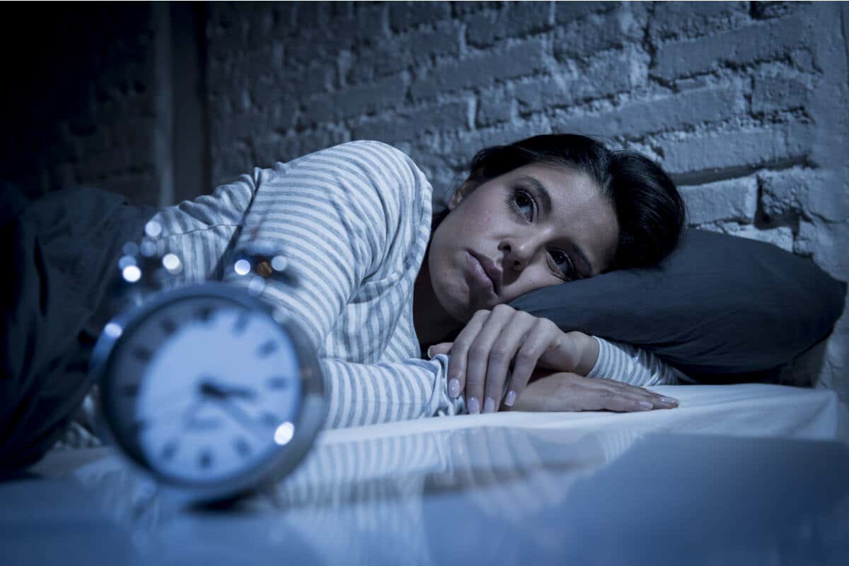 Mujer con insomnio y reloj.
